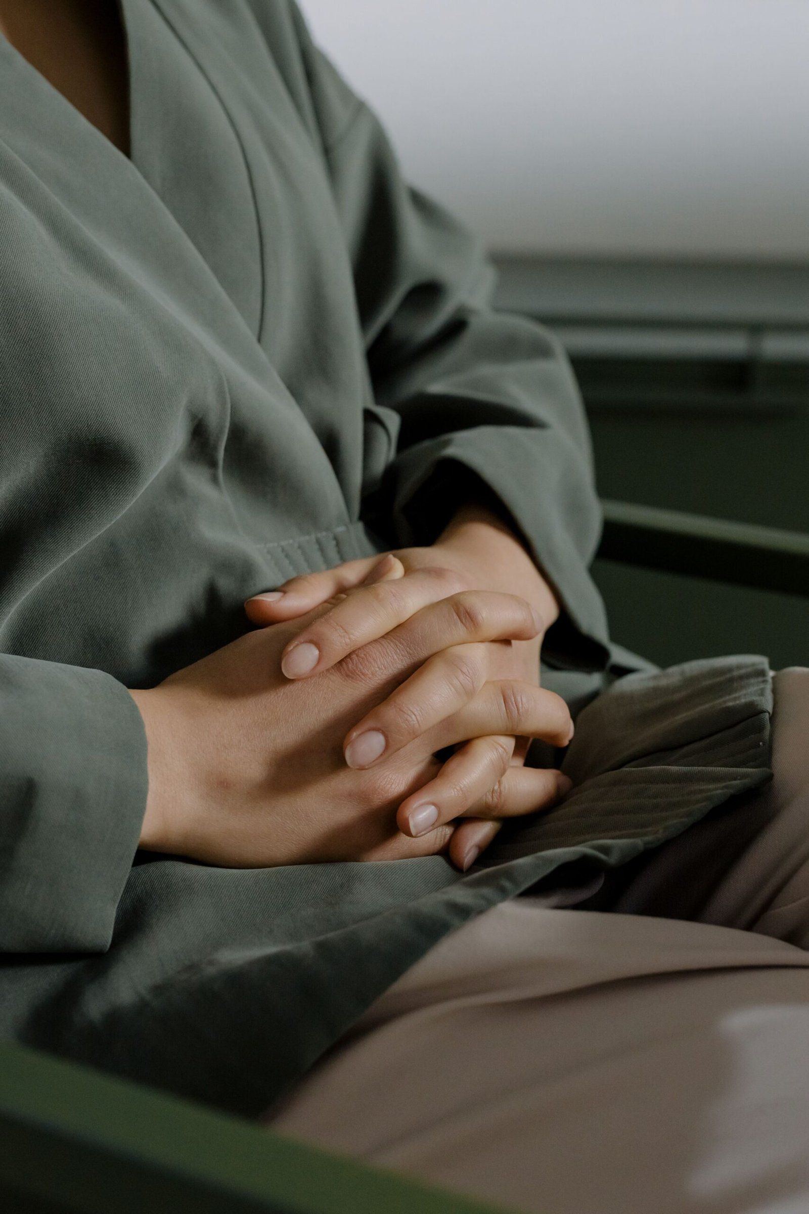 Person seated with hands gently clasped
